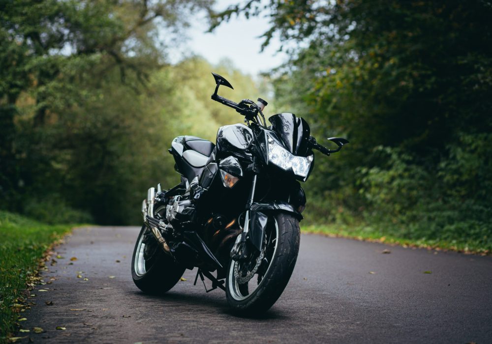 Black sports motorcycle standing on a forest road on a background of green trees
